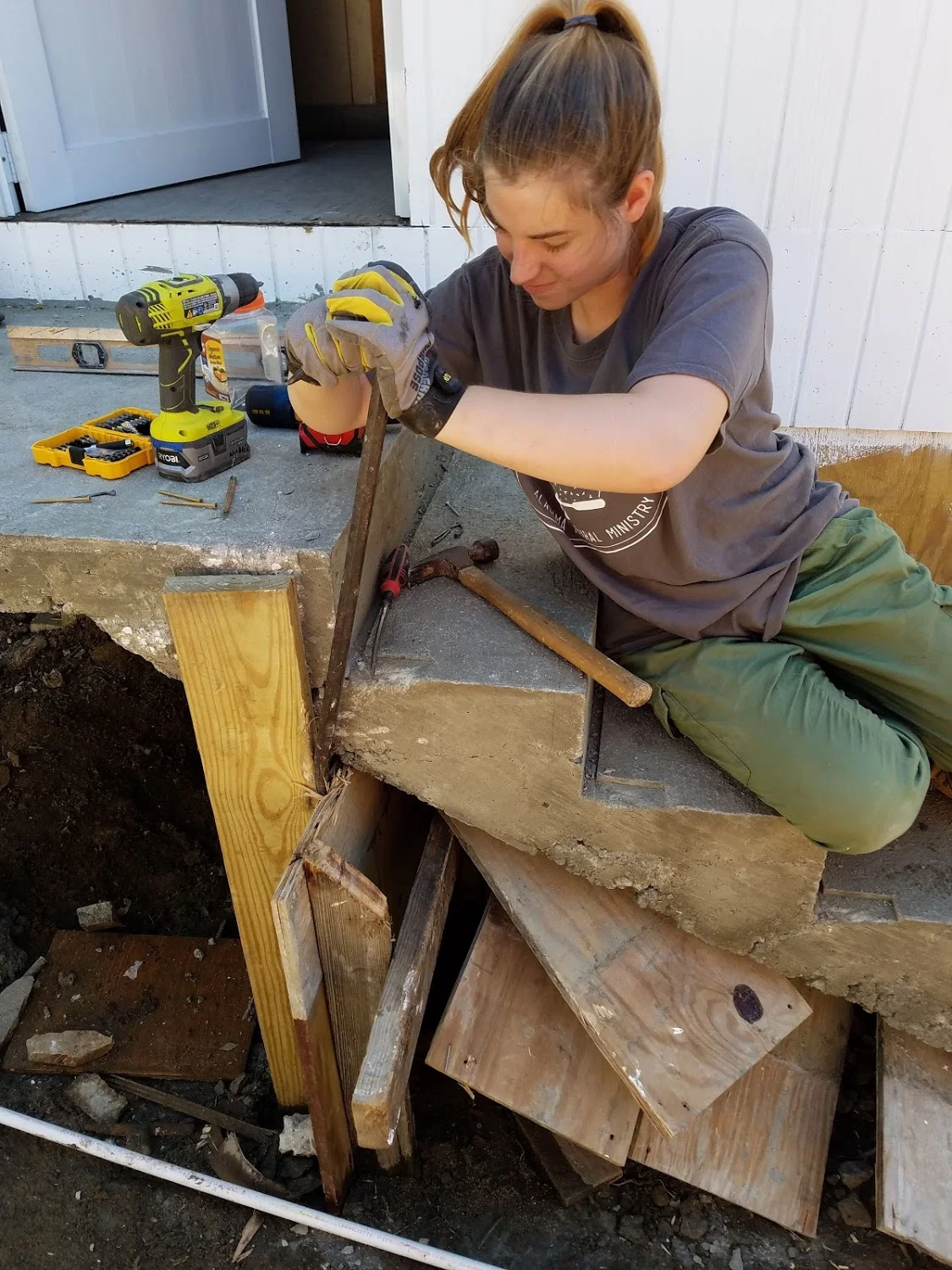 Megan Kucera tries to tear away some old wood from under the stairs