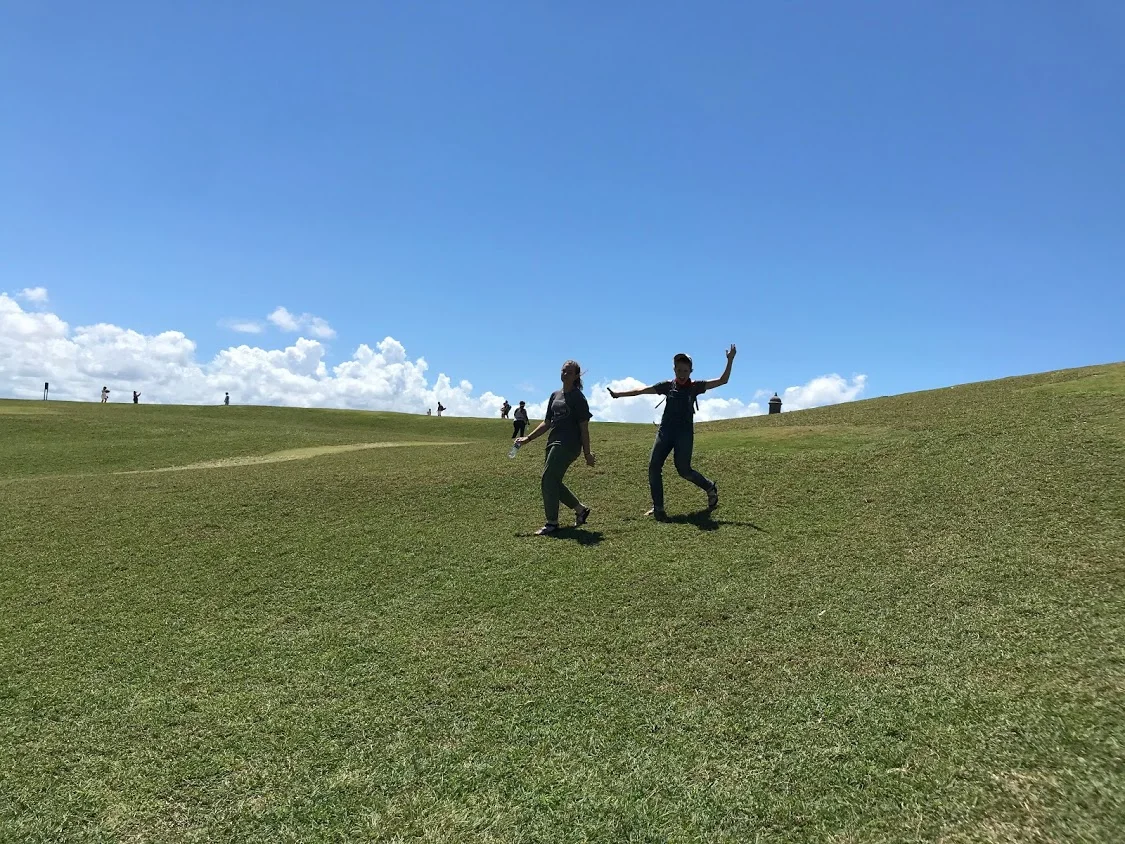 Megan Kucera and Bekah Wommack run around on a hill outside of a fort in Old San Juan while Ben Gourley explores the inside