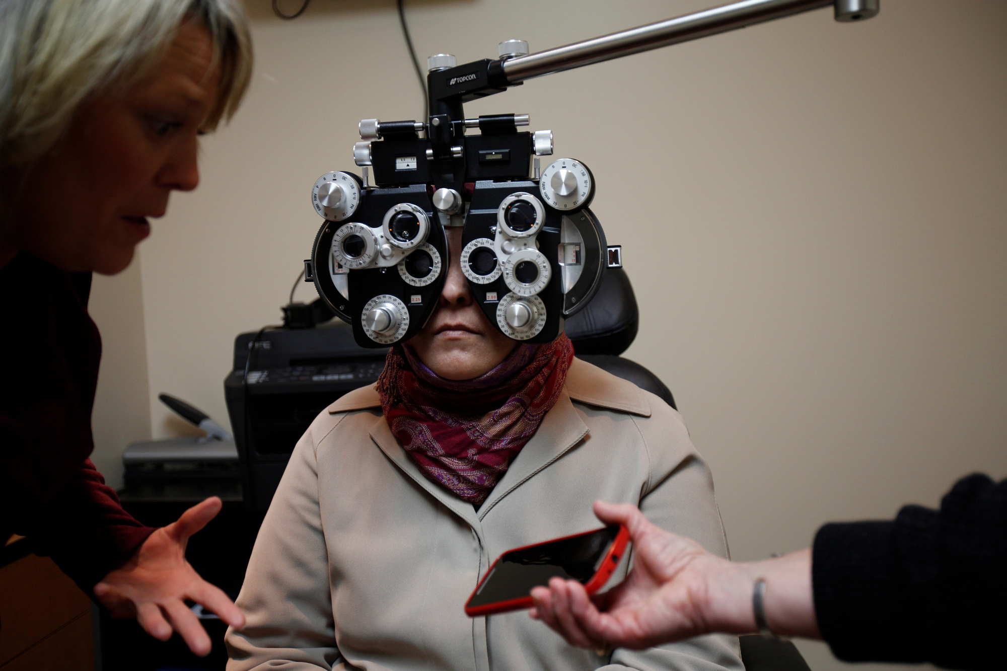  Kimberly Smith, OD, speaks to a translator on a phone that Therese Hazzard holds during Ahlam Alhamoud’s eye exam at Walmart in Evendale on Tuesday, March 22, 2016. Ahlam's glasses were held together with tape for the first five months she lived in 