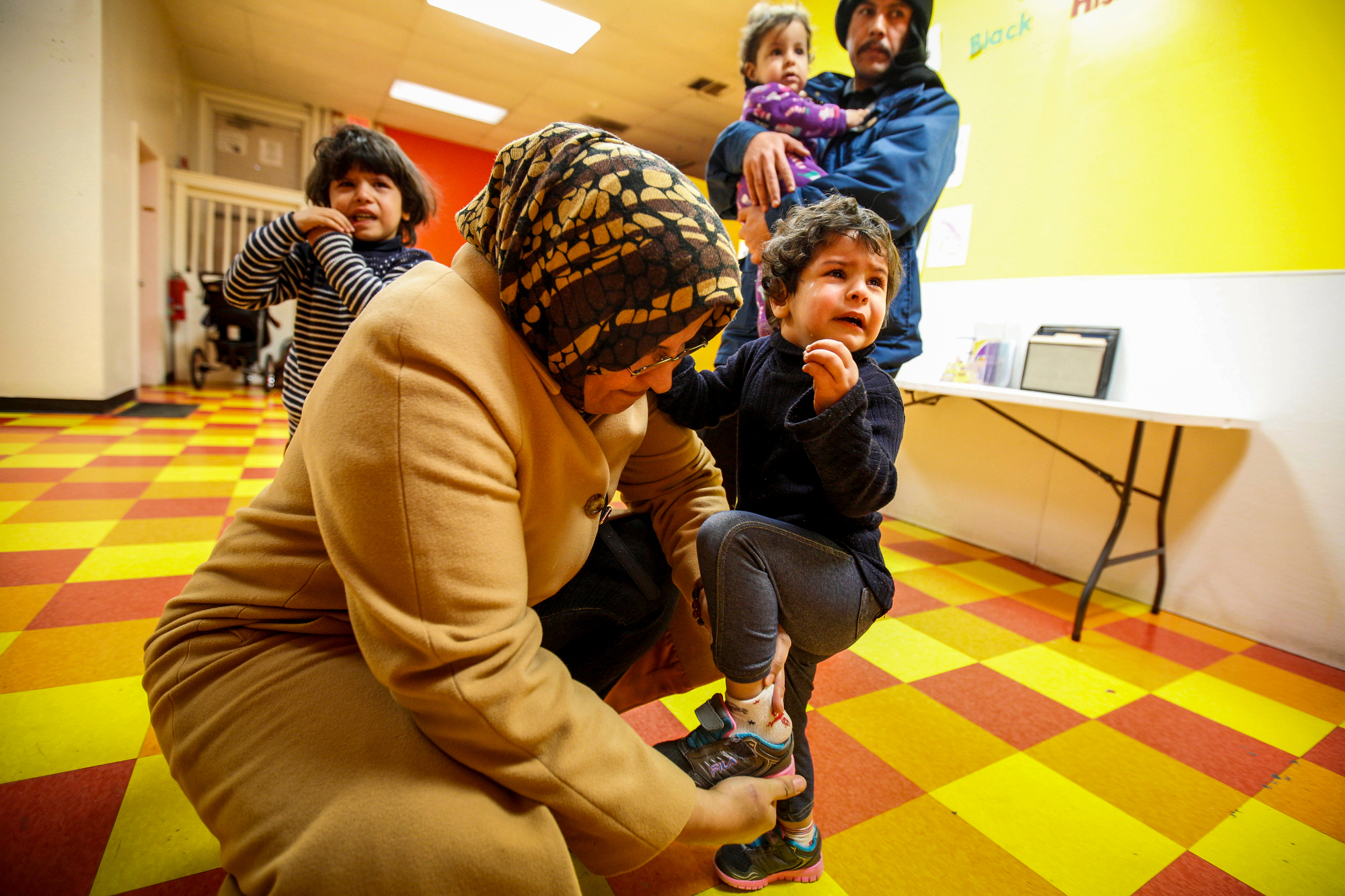  Ahlam Ahlamoud puts on Ghalia’s shoes while dropping the three youngest children off for their third day of day care on Friday, February 19, 2016. 