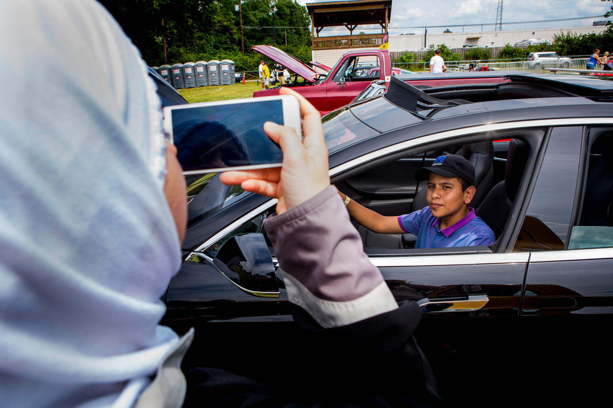  Hasan Alhamoud poses for a photo in a Tesla car at the Immaculate Heart of Mary parish festival Sunday, July 17, 2016. 