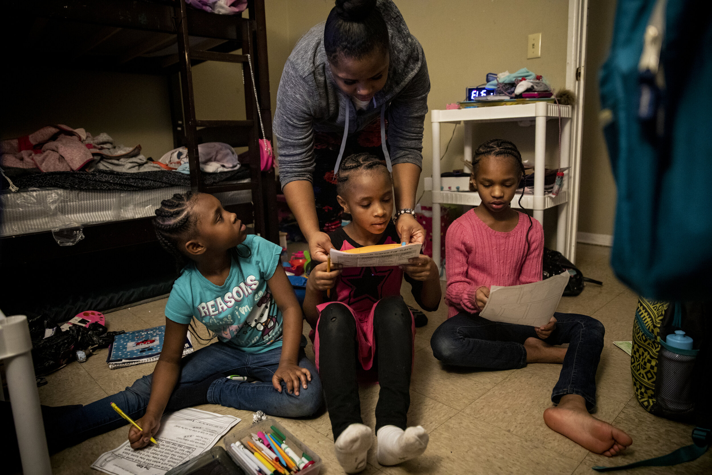  Paige Berry helps her three daughters Angelina, 7, Ajaunae, 8, and Amariyonna, 9, with their homework in the girls' bedroom in their basement apartment.&nbsp; 