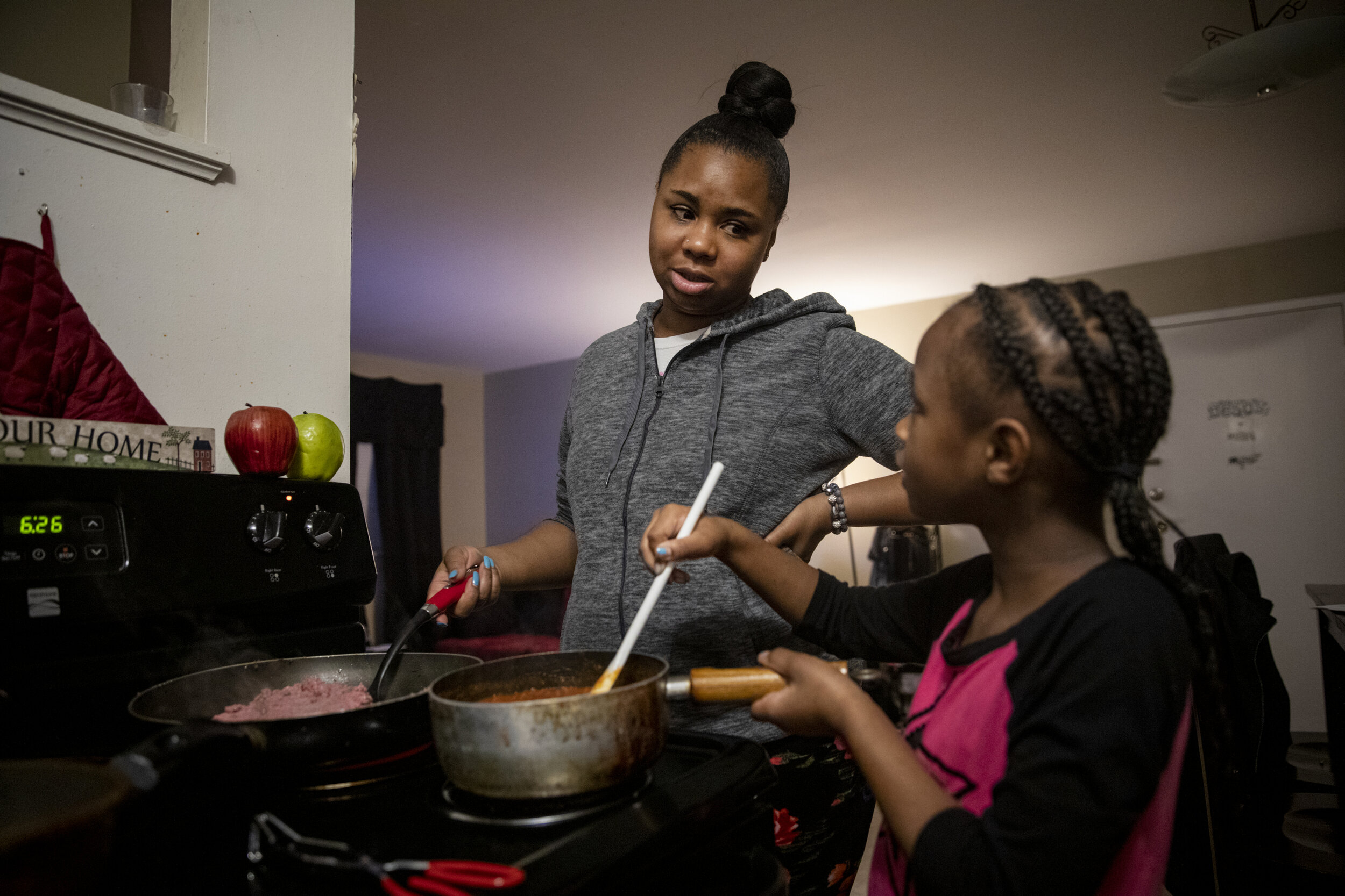  Paige Berry makes dinner with the help of her daughter Ajaunae, 8. 