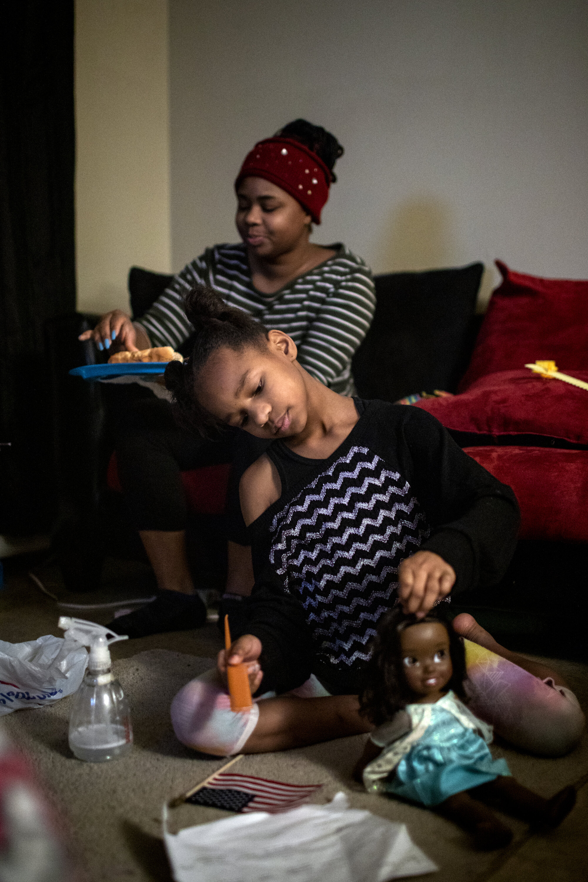  Amariyonna, 9, combs her doll's hair while her mom Paige Berry eats dinner before having to go to work at the airport.  