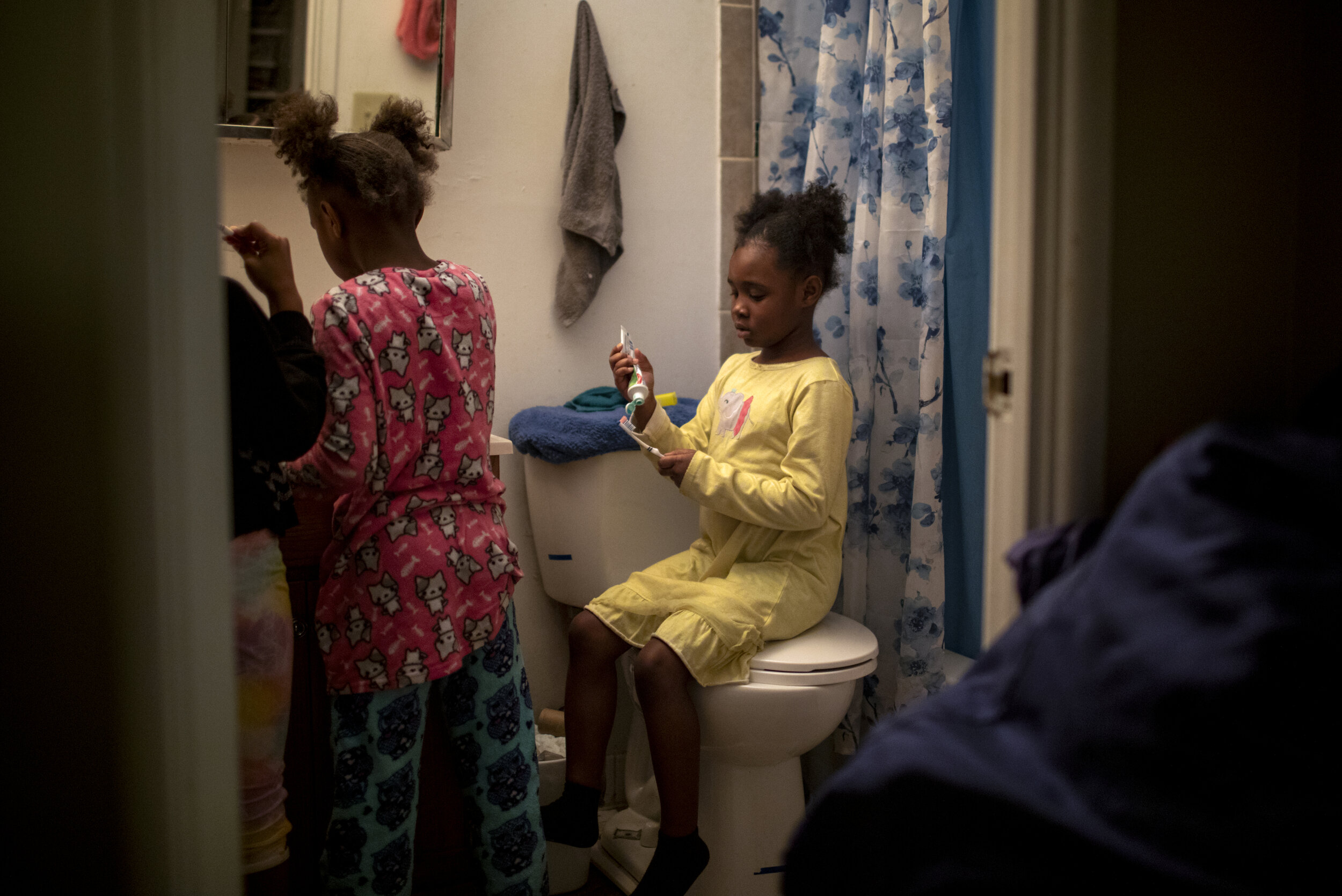  Angelina, 7, puts toothpaste on her toothbrush while her sisters brush their teeth. 