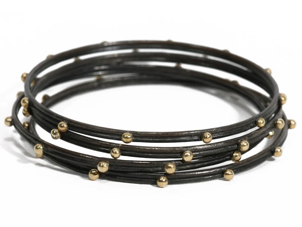 A stack of Old World Bangle Bracelets from Armenta with Gold at Reads Jewelers