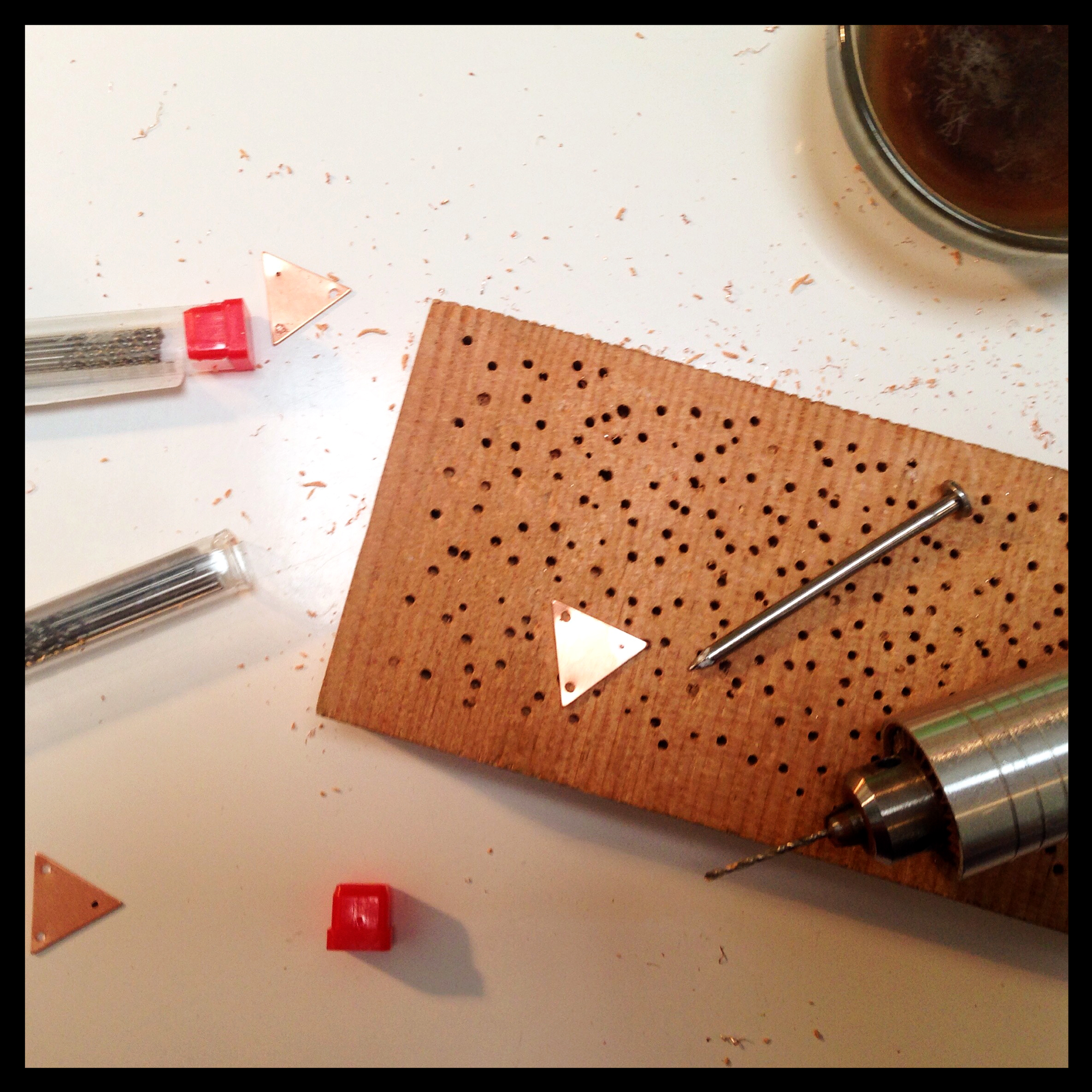 Drilling holes in copper triangles.