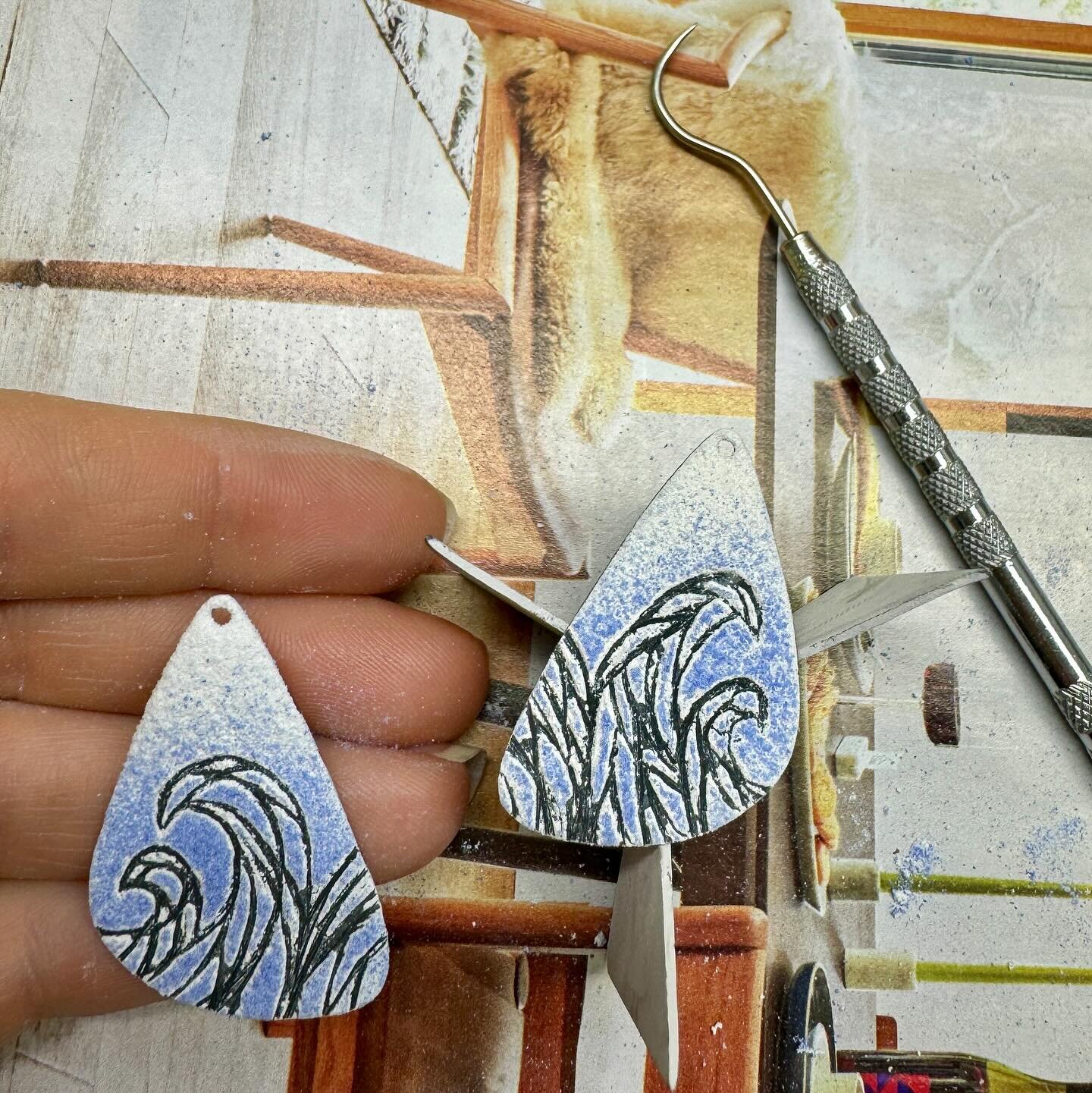 Using the sgraffito technique to draw waves on these earrings and get them ready for the kiln. Swipe to see additional process photos.