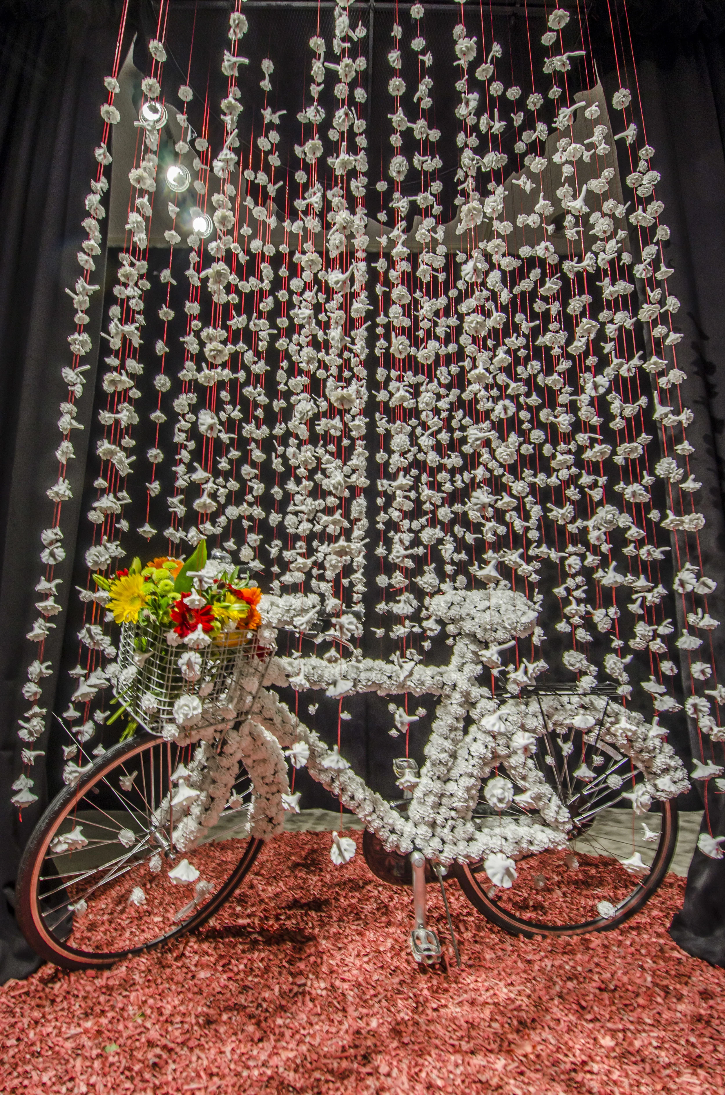 Homage to A. W ., 2016 Porcelain, bicycle, fishing wire, round metal grid, black fabric curtain, fire cracker paper, fresh flowers