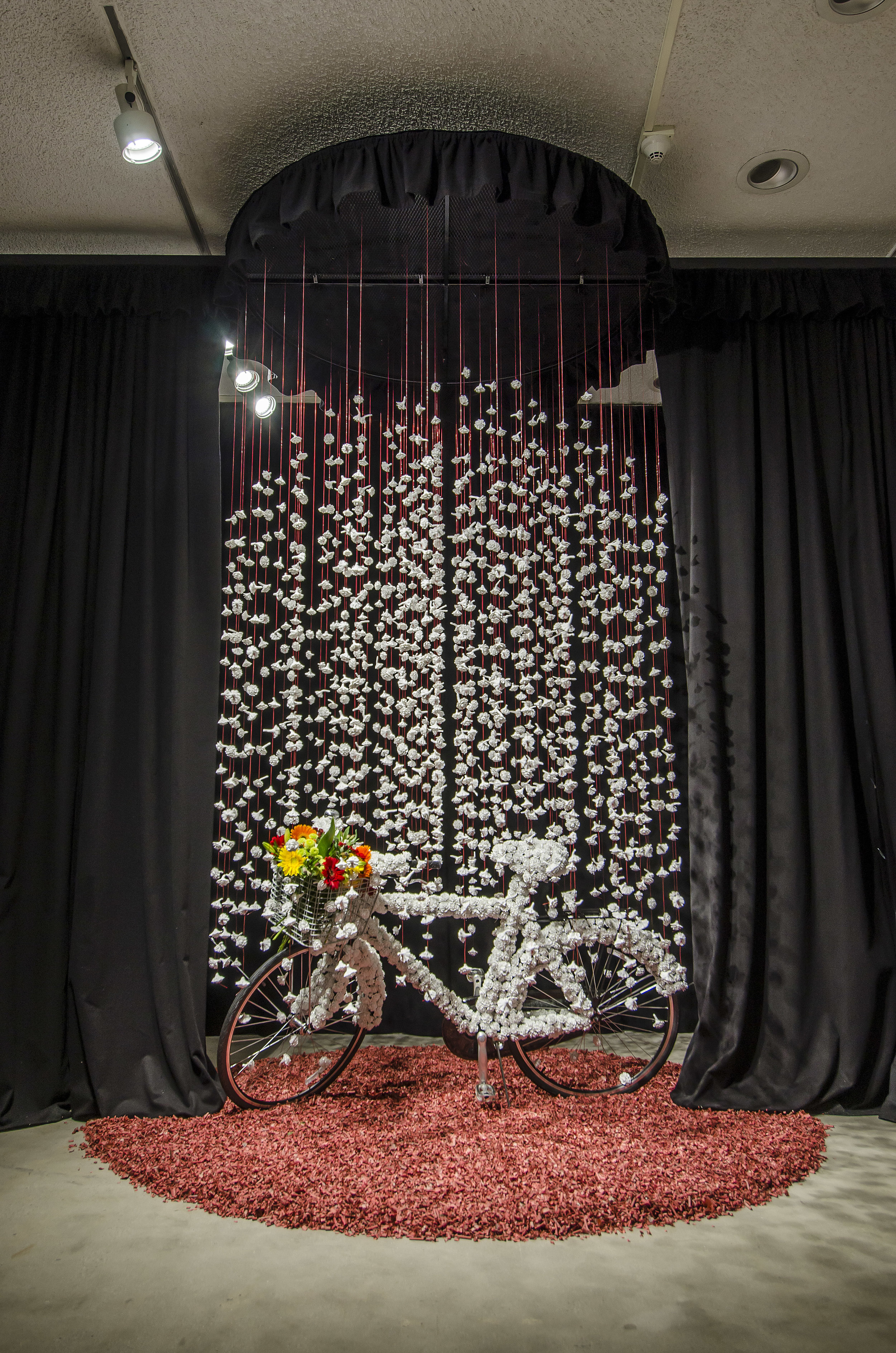 Homage to A. W ., 2016 Porcelain, bicycle, fishing wire, round metal grid, black fabric curtain, fire cracker paper, fresh flowers