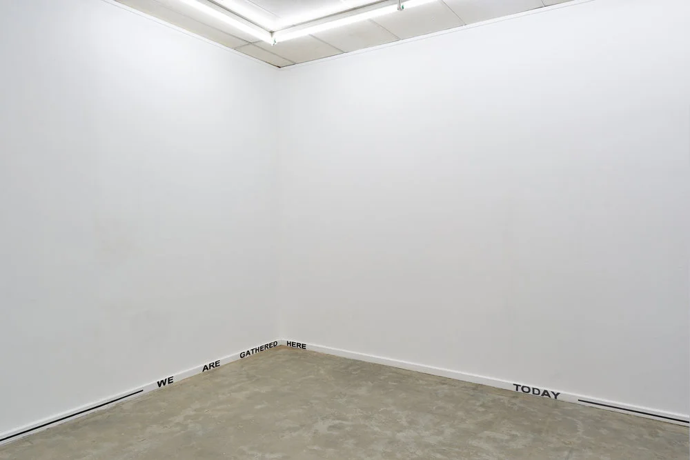 Grace Marlow, WE ARE GATHERED HERE TODAY , black painted text and line on the gallery skirting boards, in Who speaks for a community? curated by Bella Hone-Saunders, Sister Gallery, 2017. Photography by Christopher Arblaster.