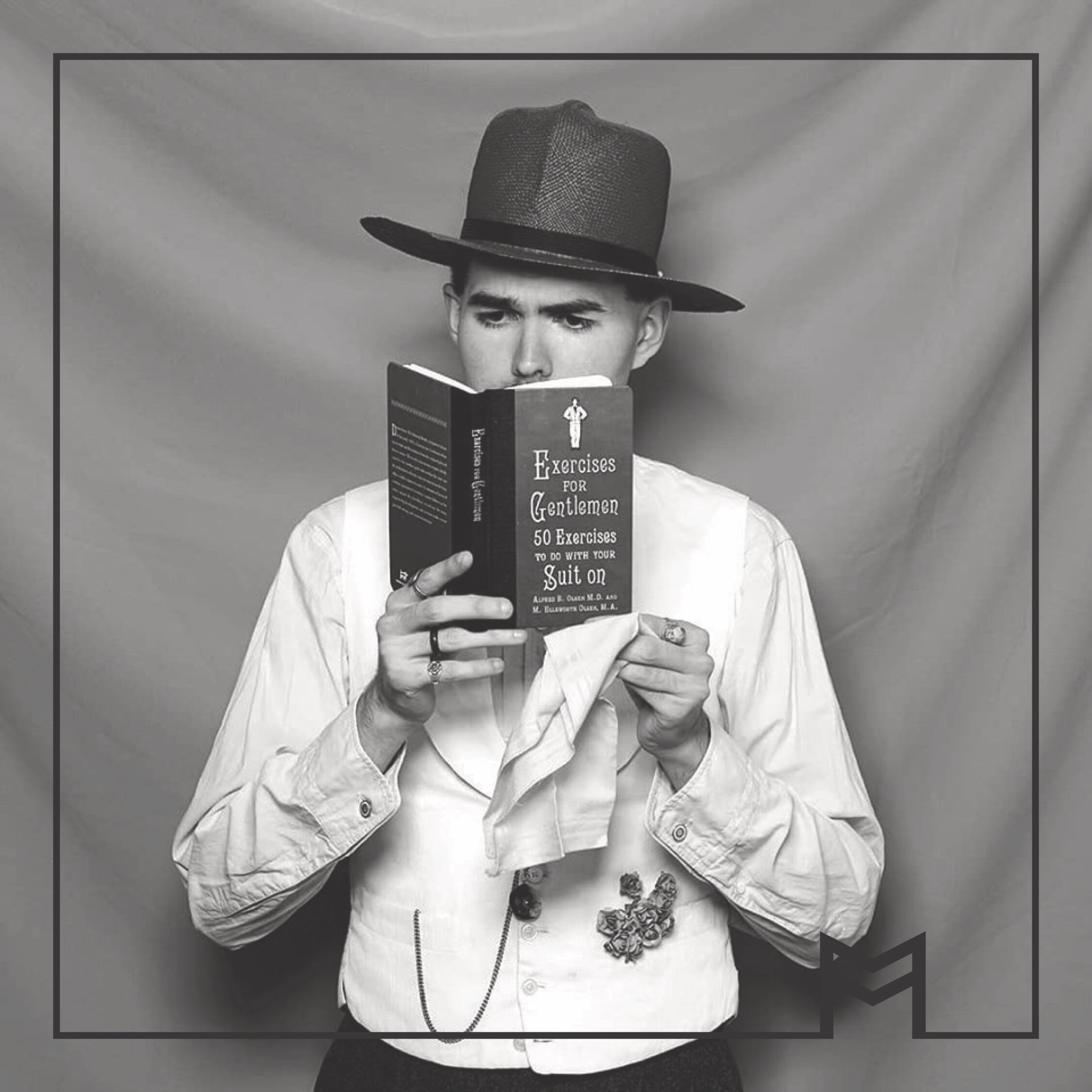 black and white image of a person wearing a hat and reading a book