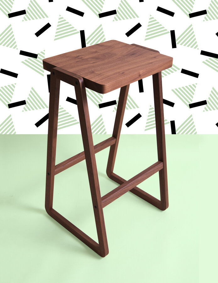 image of a wooden stool in front of a mint coloured background