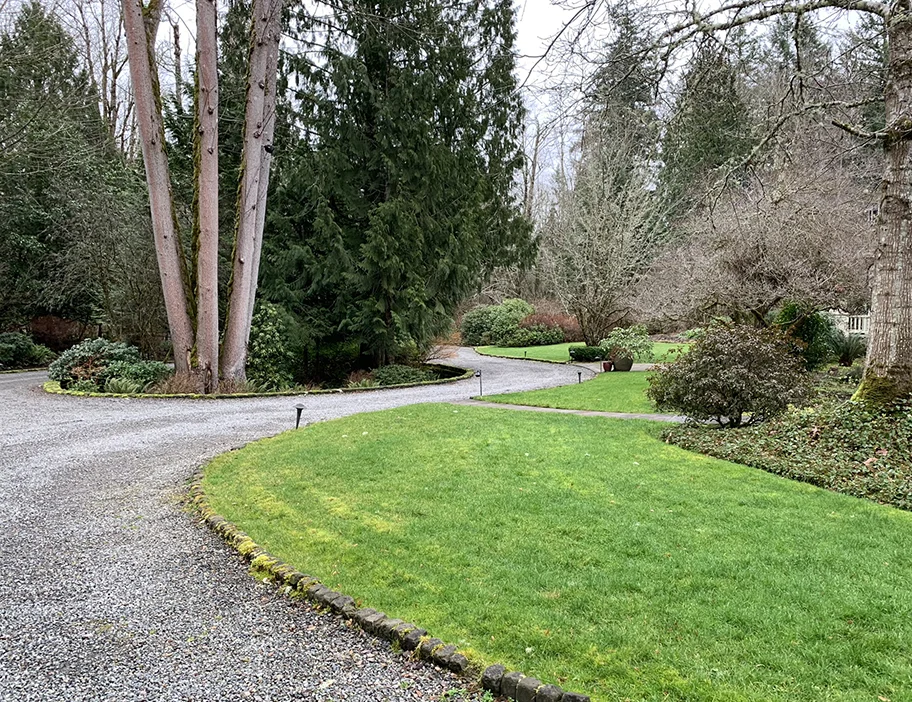 Currently the driveway includes a turnaround in front of the house with the only visible parking near the attached garage and the drive, which continues on to the guest house.