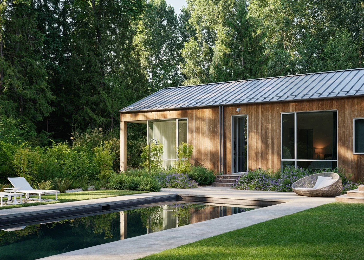 Poolside at the Interurban Residence. The house and garden are nestled within five acres of Pacific Northwest forest. A layered planting palette of native and ornamental species surrounds the swimming pool, with woodland walking paths weaving through
