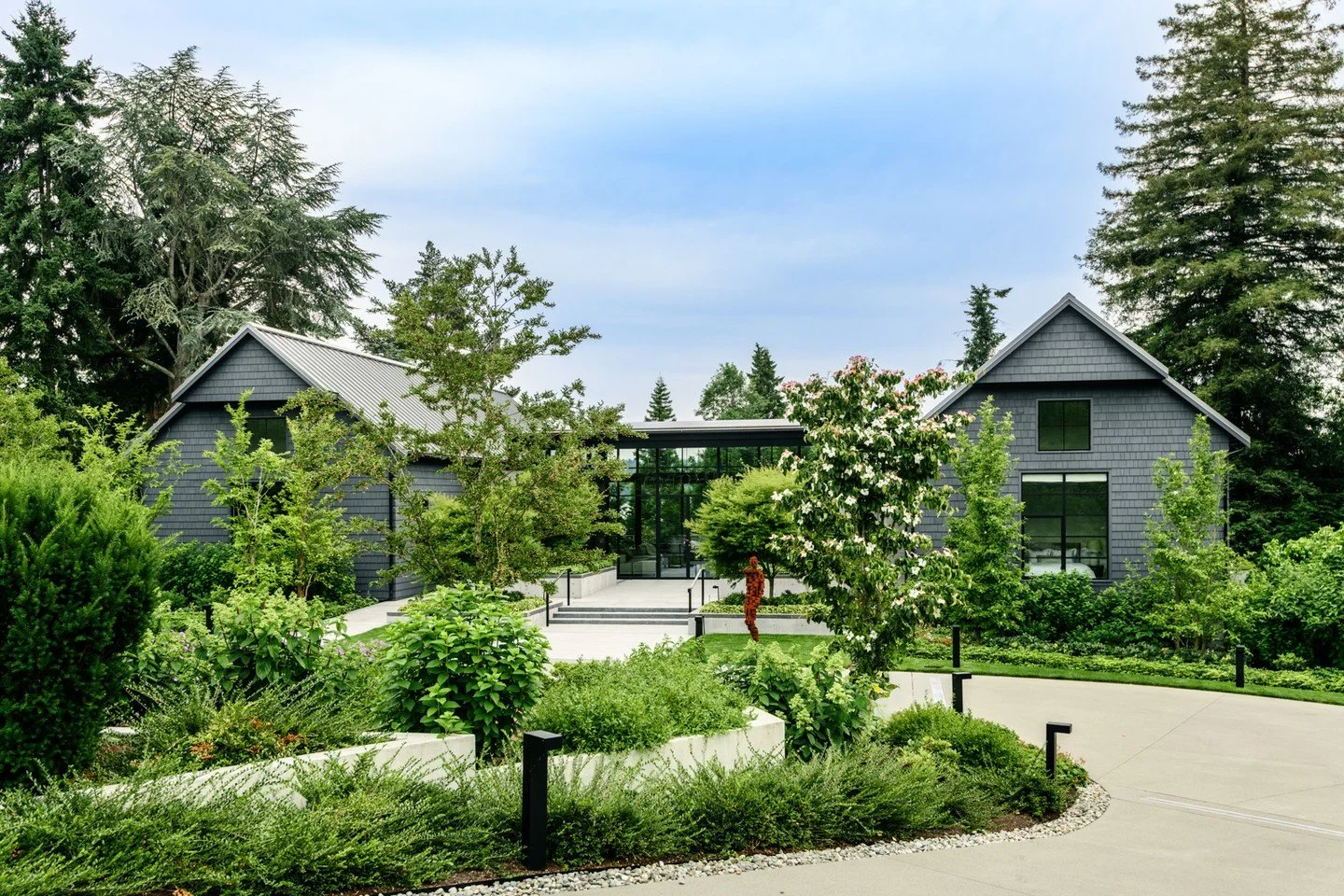 Privet honeysuckle, Yaku Dreamland Rhododendron, and Oakleaf Hydrangea line the  entry drive at the Garage Pavilion. 

Architect: Patrick Byrne Architects - @patrickbyrnearchitects
Interior Designer: LeeAnn Baker Interiors - @leeannbakerinteriors
Str