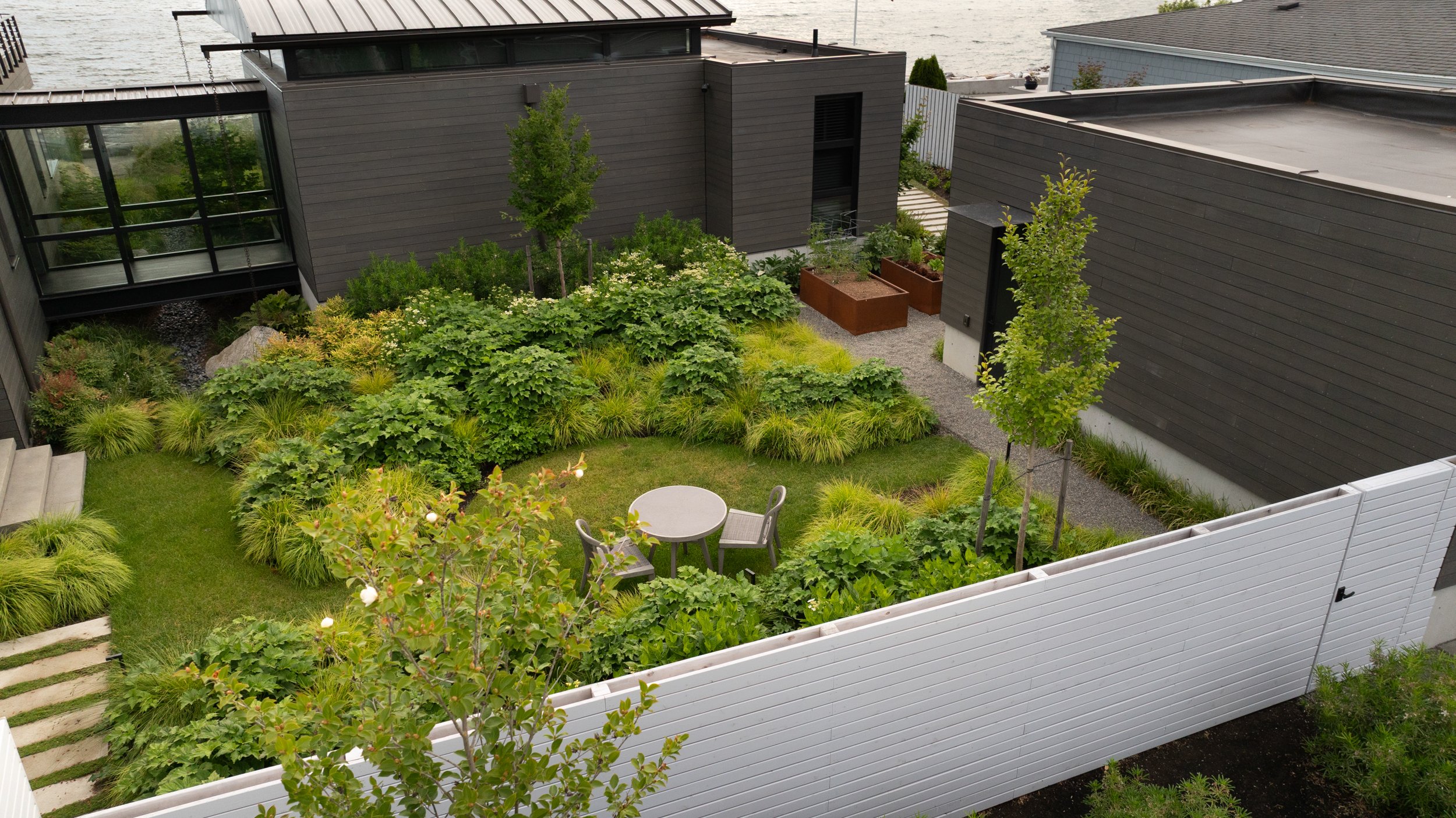 Private fenced garden with seating area features lawn area and hydrangeas.