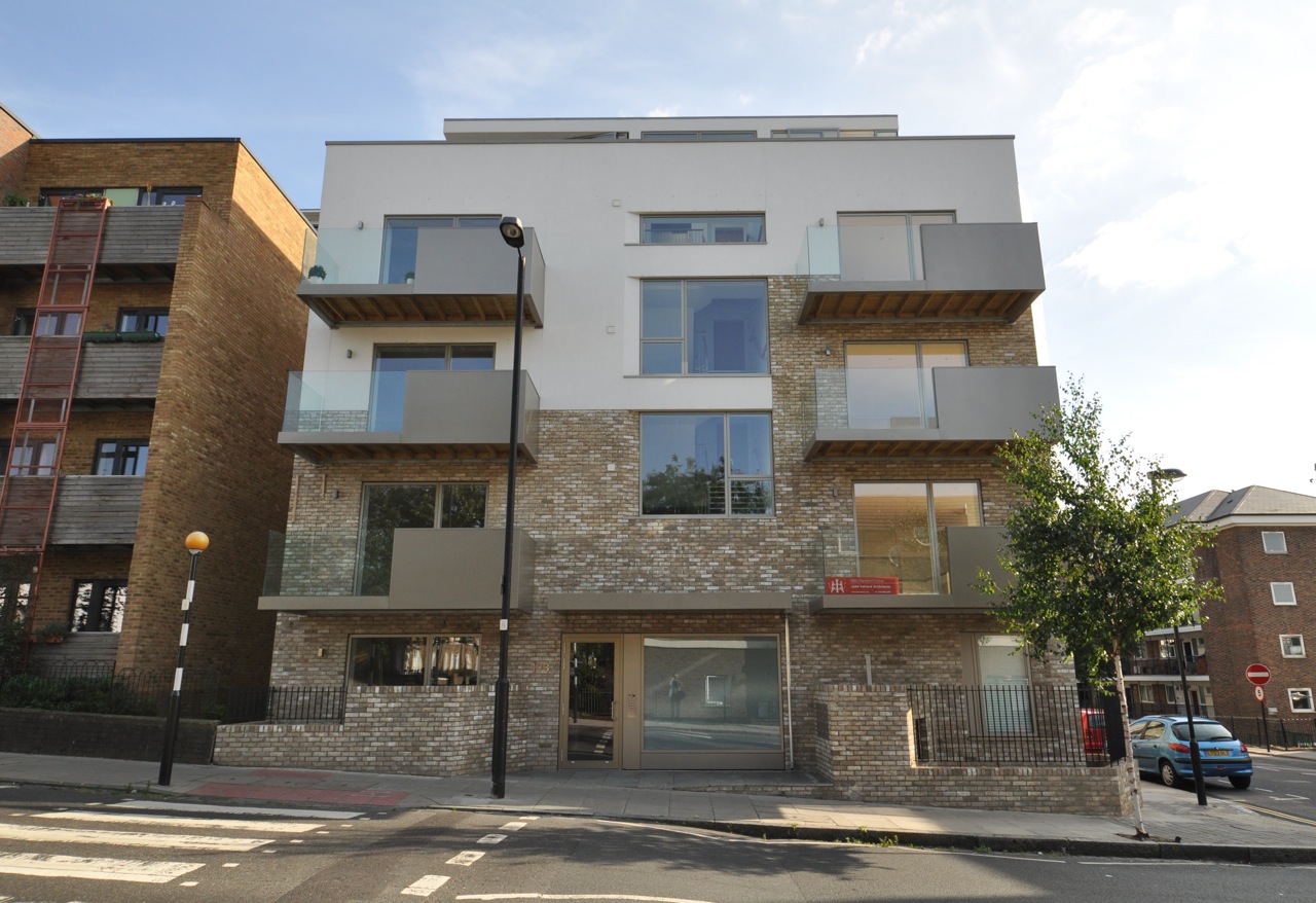 This is a new-build block for eight 2-bedroom flats and a B1 office unit. The intention for this project was to produce enjoyable, sustainable homes, with generous social spaces, good daylight, robust attractive materials and innovative contemporary design that contextually integrates with the local area. The lower walls are in buff-yellow bricks, which meet the upper white acrylic render to show the outline of the previous pub. The bronze-anodised aluminium clad balconies – a reduction of this outline – are half glazed (for views to the adjacent park) and half metal-panel clad. Anodised aluminium panels clad the northwest-facing projecting-bay. The geometry of the projecting-bay is echoed in the splays to the window reveals, the 4th floor angled living room wall, the south-facing ground level extended area, and the garden walls, to unify and give presence to the building. The window splays supply modeling and depth to the facades and improve daylight levels and views. Reception/ kitchens are triple aspect. Air source heat pumps provide the underfloor space heating and hot water to all flats. Thermal insulation levels well exceed current building regulations; extensive green sedum roofing and many other environmental features have been introduced. The design achieves the best standards of inclusive internal layout (the flats, communal spaces and facilities meet or exceed Lifetime Homes criteria and Islington Accessible Housing SPD requirements). The building is designed and constructed to Code For Sustainable Homes Level 3. The building has been studied by students from the London Metropolitan University, and used as a case study for their sustainability and environmental architecture course. 103 Copenhagen Street was shortlisted for the Brick Awards 'Best Housing Development 6-25 units'; and was a finalist for the 2014 London Regional LABC Building Excellence Awards 'Best High Volume New Housing Development'. London Open House 2014. © jake ireland architects 2007 - 2015