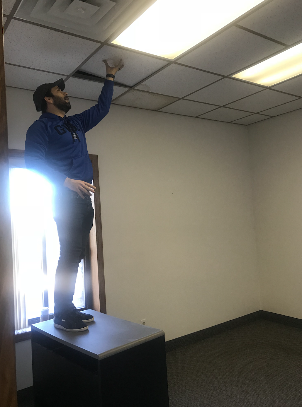 Before - Here's Justin removing a ceiling tile to see what was above the drop ceiling to know if we could remove it or not. This was a pivotal moment in the initial office tour. 
