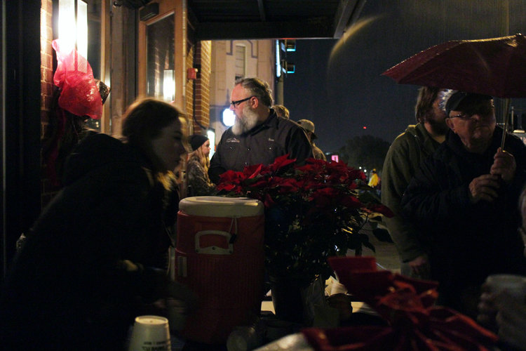 a group of people congregating around a table outside of a restaurant