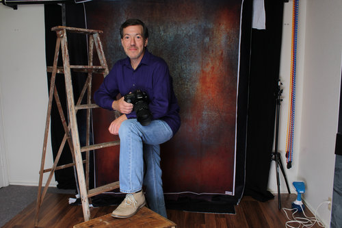 a picture of a photographer posing with a camera in a studio