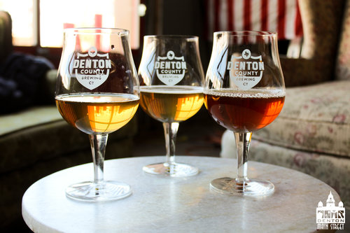 a picture of denton county brewing company glasses with some beer in them inside a bar