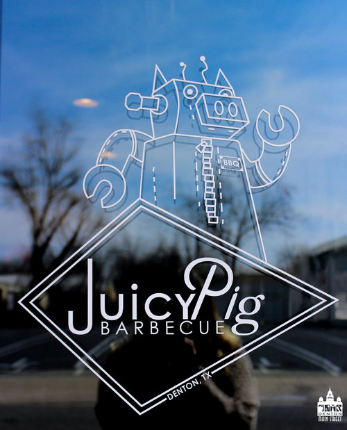 a picture of the door of juicy pig with their robot pig logo