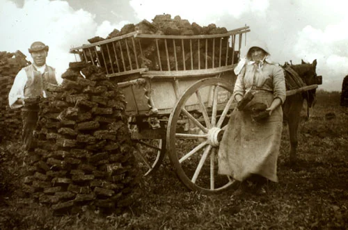 An Irish couple loads turf into their cart (c, 1905) 