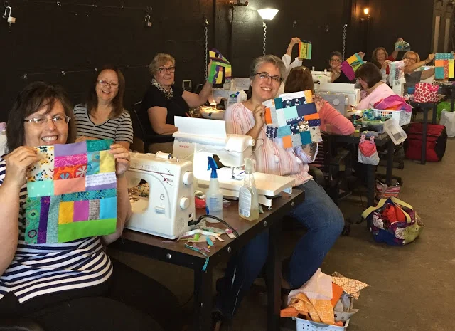 Quilters showing off their improv starter blocks