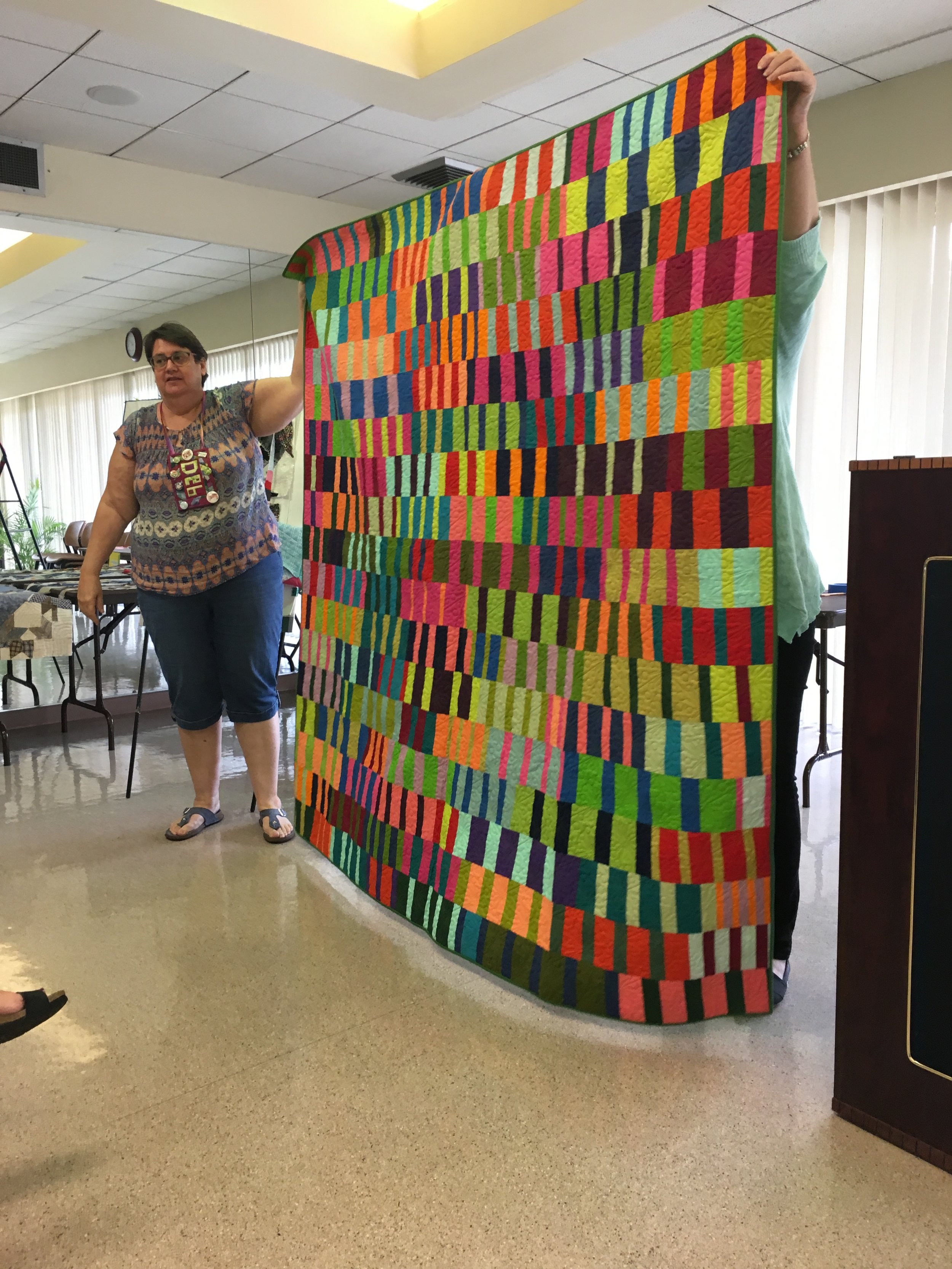  Debbie with her finished quilt. Started in a Tara Faughnan class at QuiltCon 2017. 