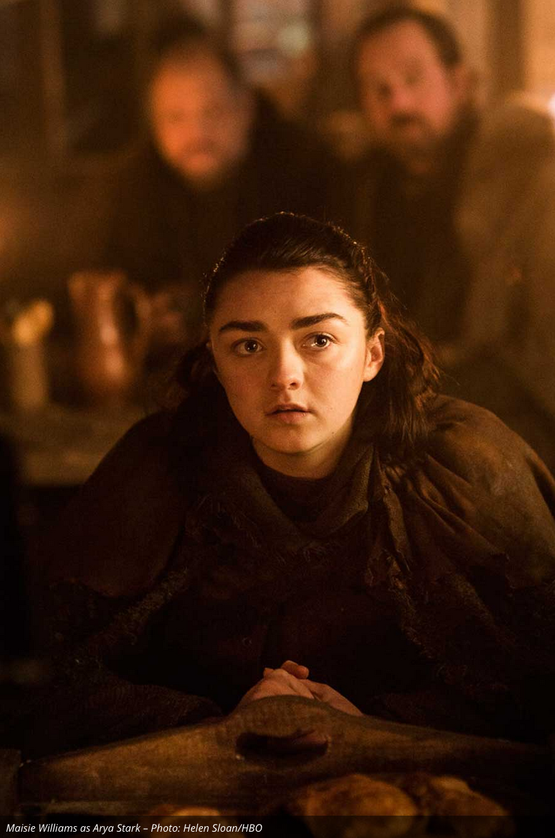 Arya is in an inn or tavern listening to someone intently. We don't know her specific location, but my best guess is that she is still traveling around mid-Westeros plotting her next move.
