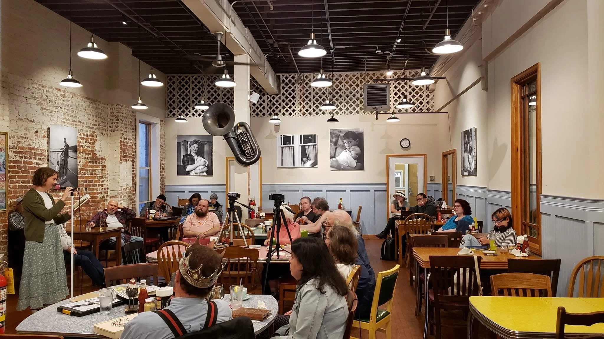 A poet reads at the microphone to a seated audience at Everett Poetry Night inside The Sisters Restaurant
