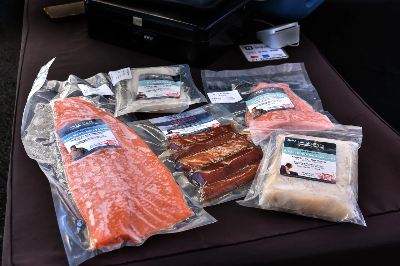 Vacuum-sealed wild Alaskan sockeye, coho, black cod, and weathervane scallops from Sea to Shore, each labeled with the fisherman who caught it