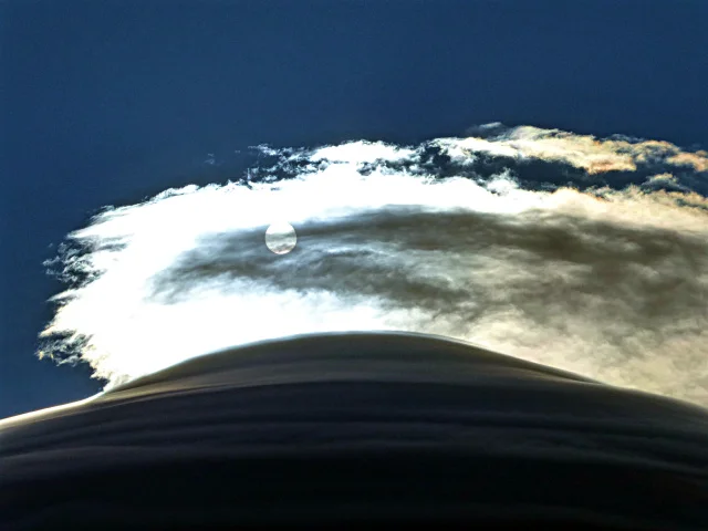  The rising sun brightening the thin cloud above huge cap clouds 