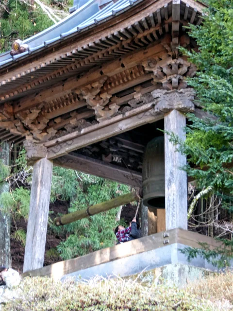  A soft ring of the hanging bell of Rengeji temple being struck by a mother with her baby 