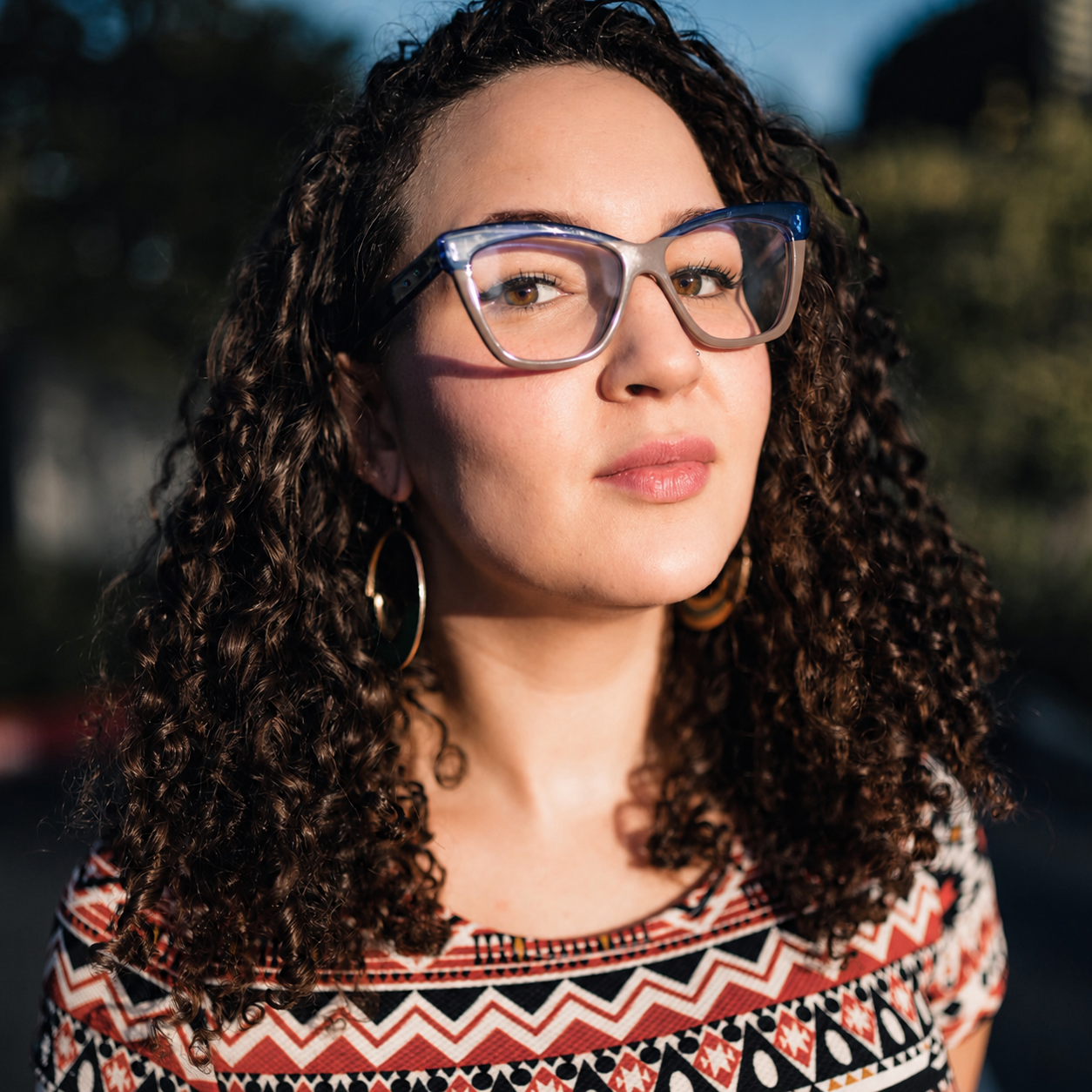 K'Yala, smiling, wearing glasses and a necklace, captured in a profile picture format.