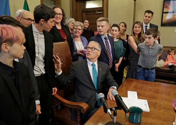 Washington State Governor Jay Inslee spoke to Katrina Spade, the founder of Recompose, as he signed a bill into law that allows licensed facilities to turn human remains into compost. Image via New York Times