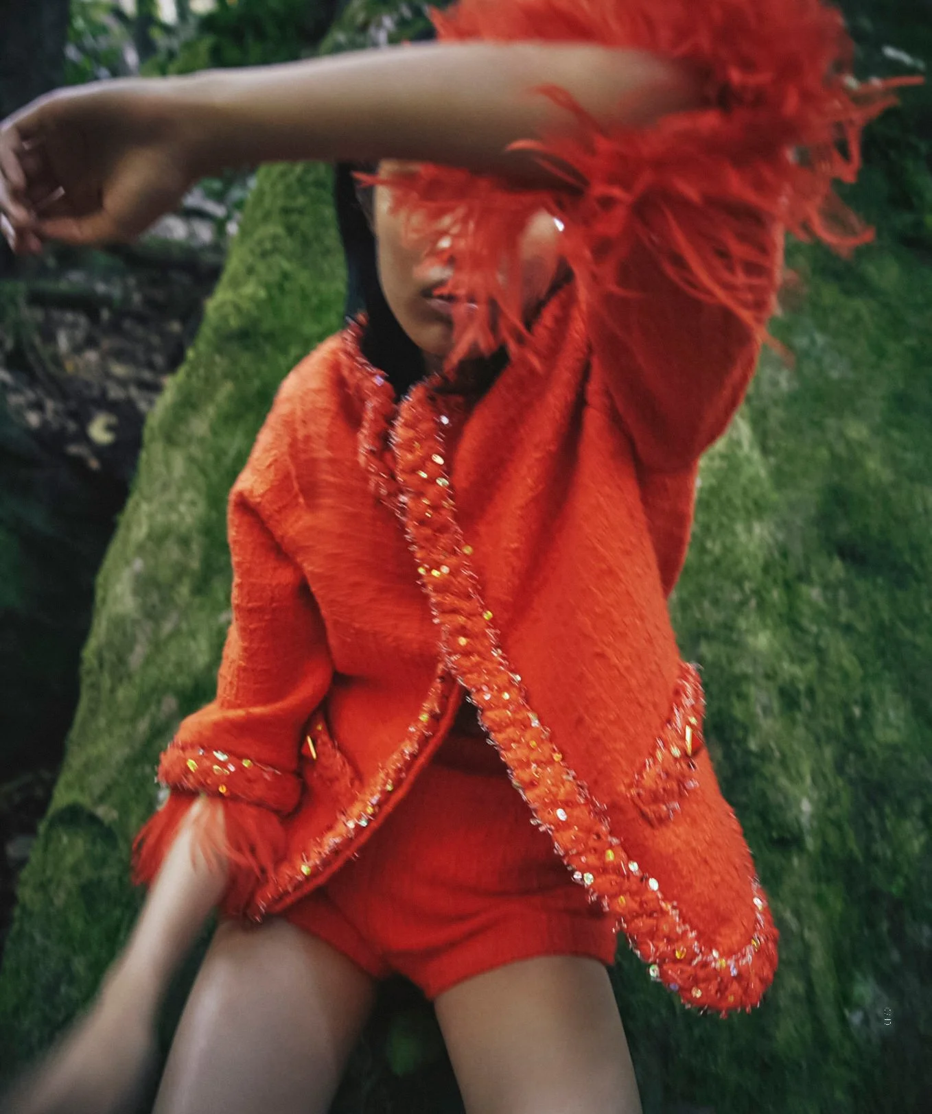 Model wears red-orange Chanel jacket with feathery cuffs.