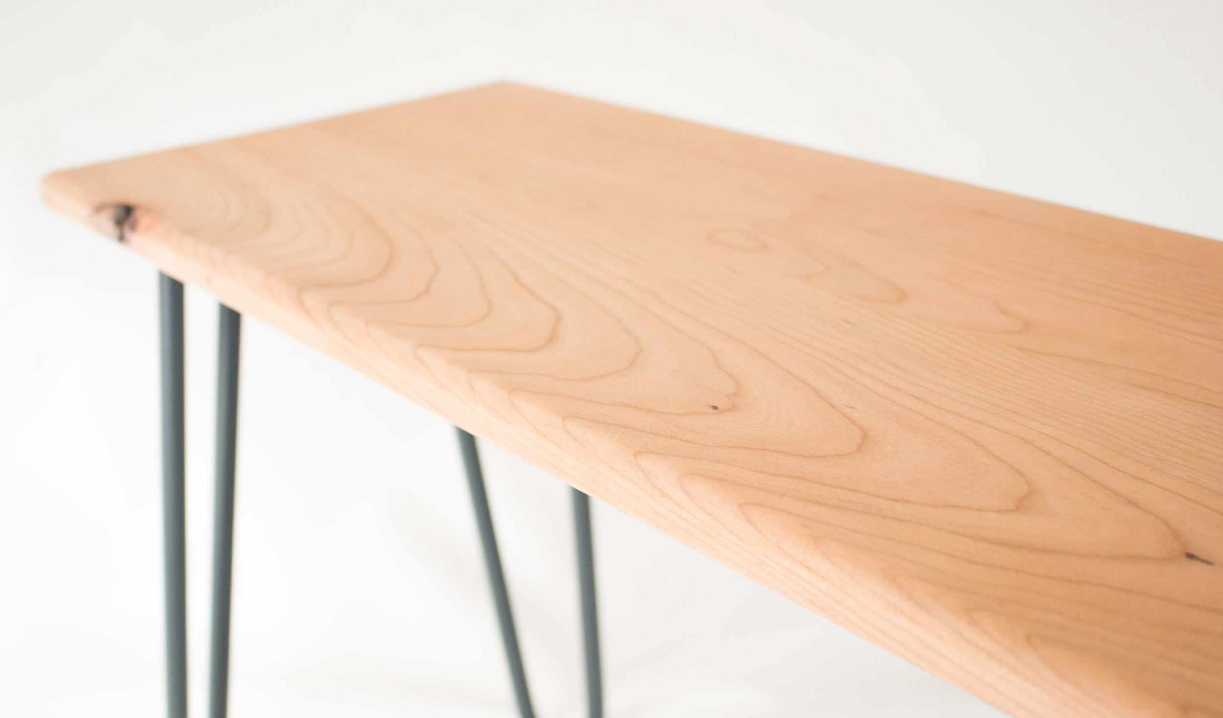 Cherry wood bench by Cord Industries, shown with lacquered steel hairpin legs.