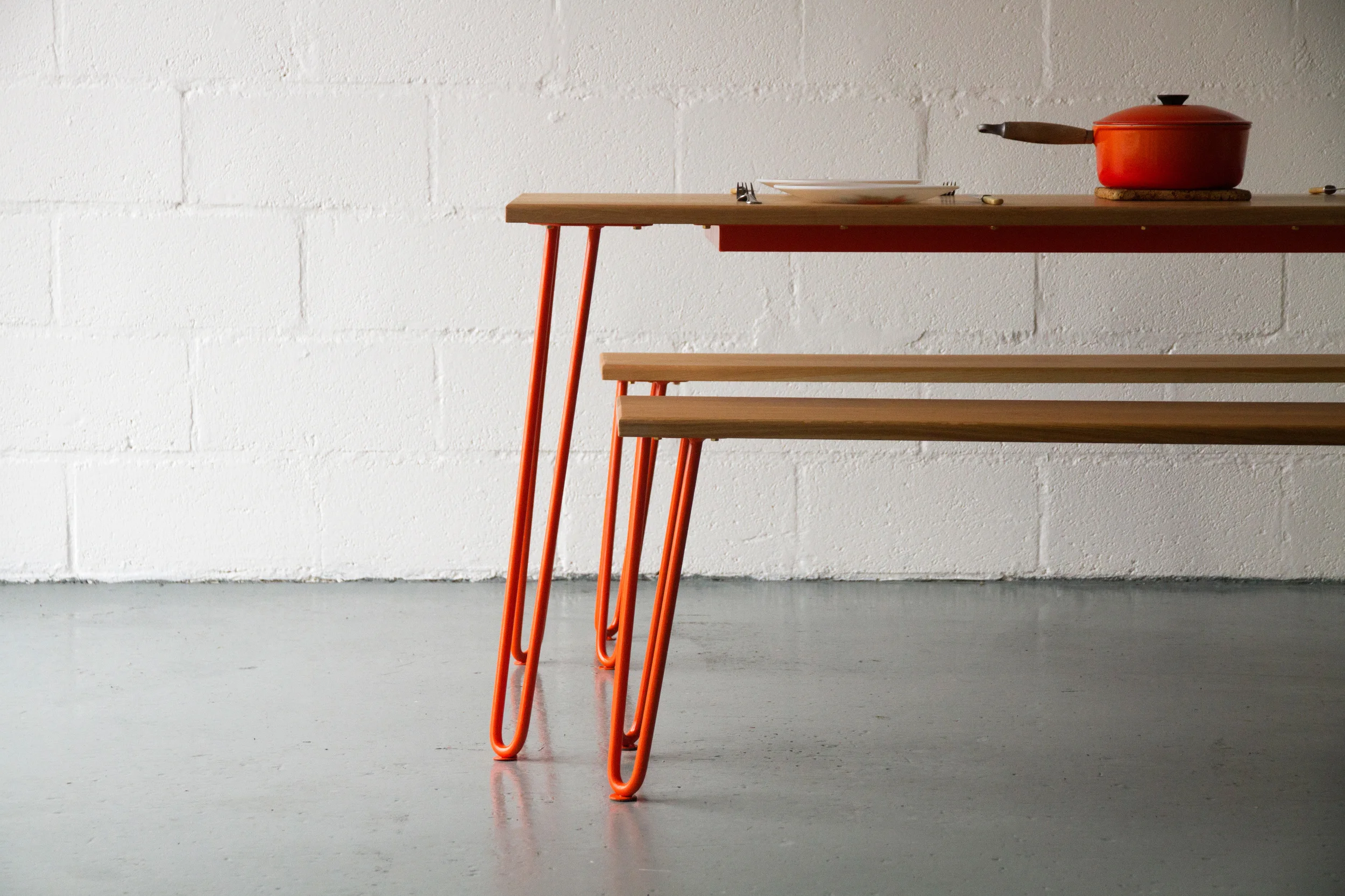 Cord Industries hairpin leg dining table, in oak with orange legs.