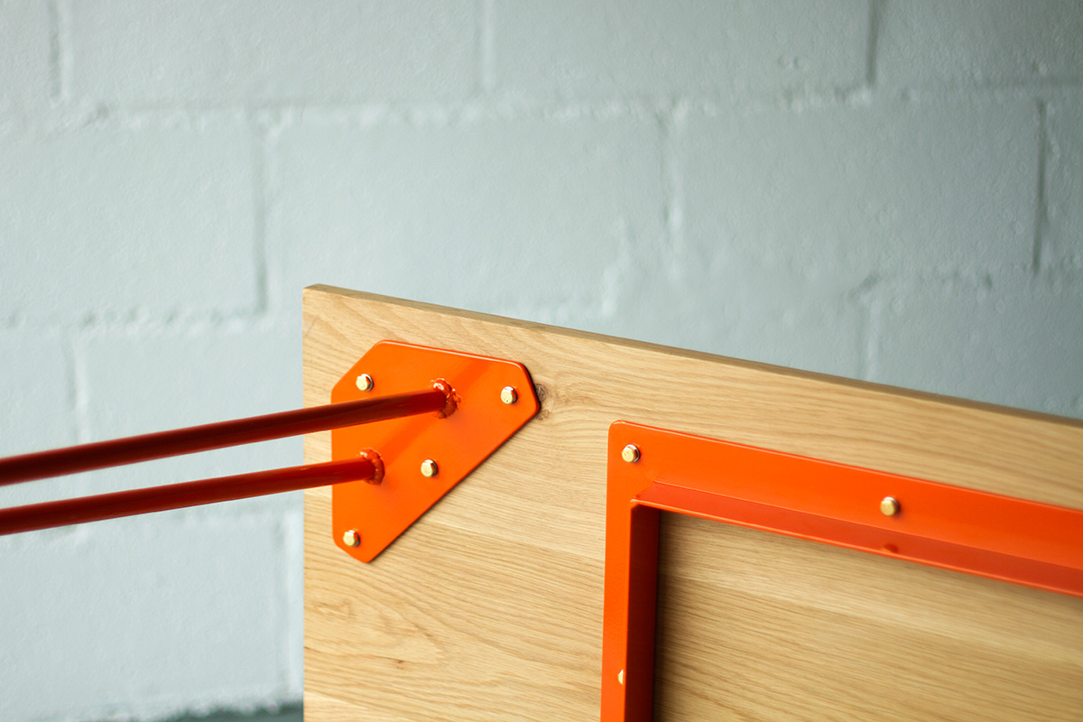 Hardware detail of Cord Industries hairpin leg dining table, in oak with orange legs.