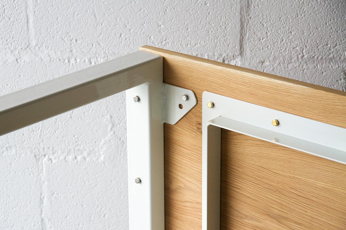 Close-up detail shot of hardware on Cord Industries Nola dining table in oak with white legs.