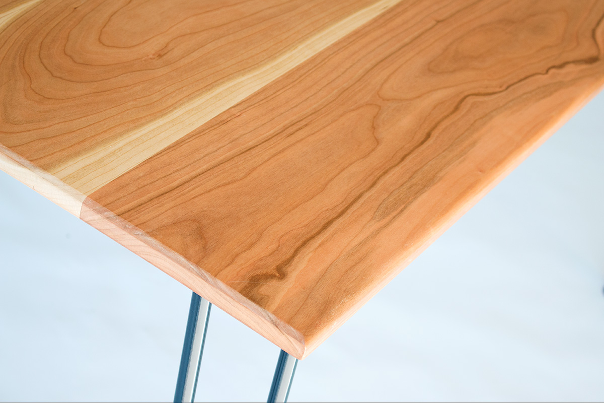 Cherry wood dining table by Cord Industries, shown with lacquered steel hairpin legs.