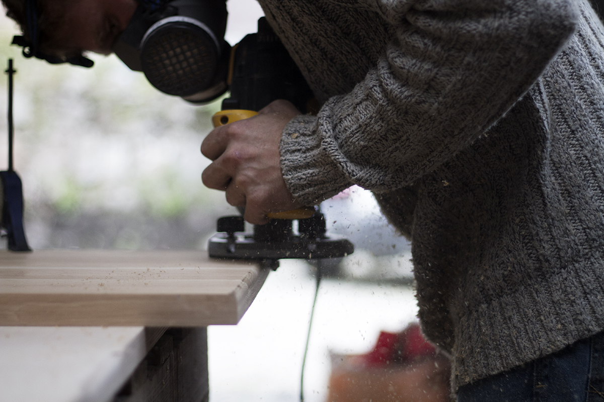 Edges of oak coffee table top being routed to a rounded edge at the Cord Industries workshop.