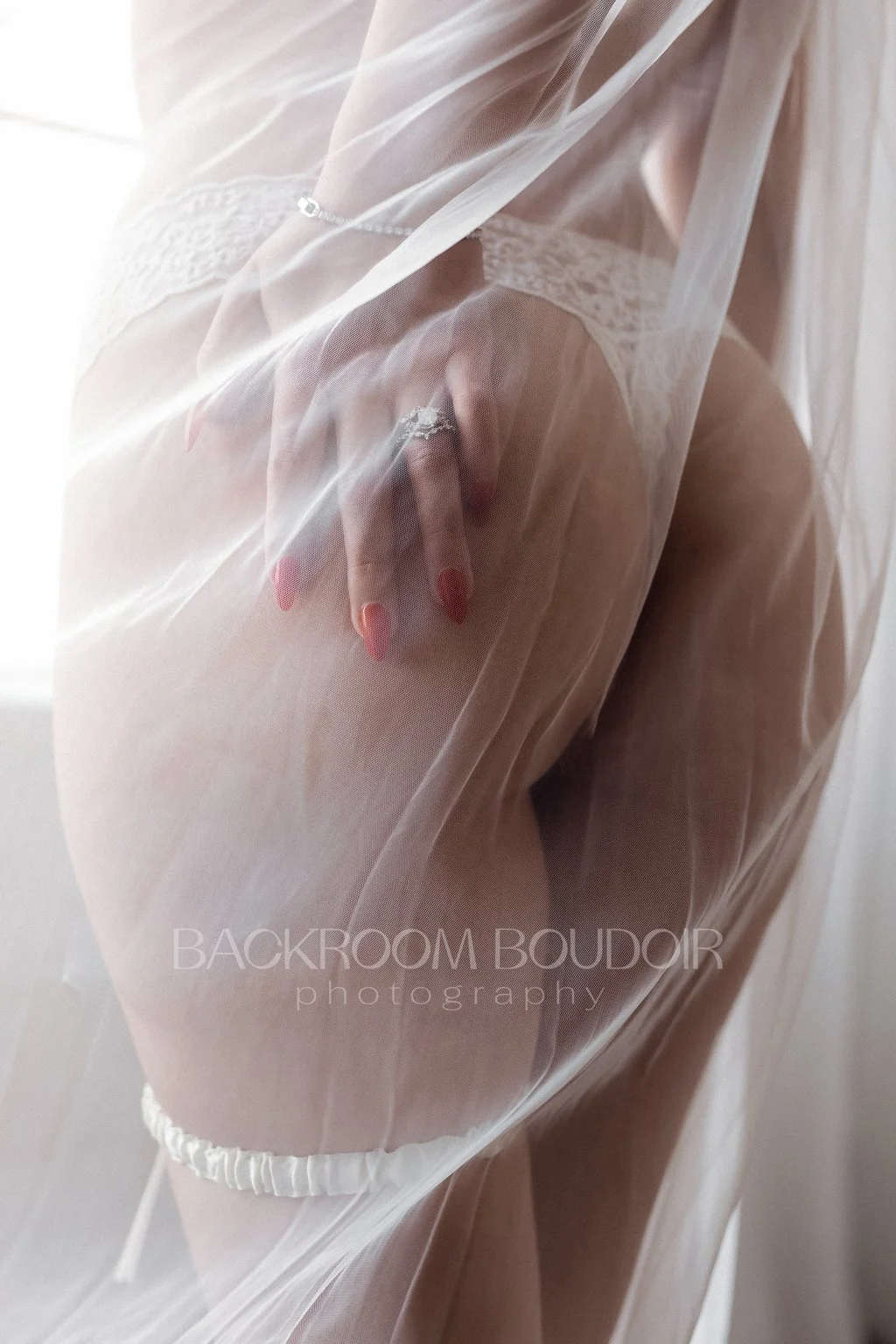 Woman behind a wedding veil holds her butt