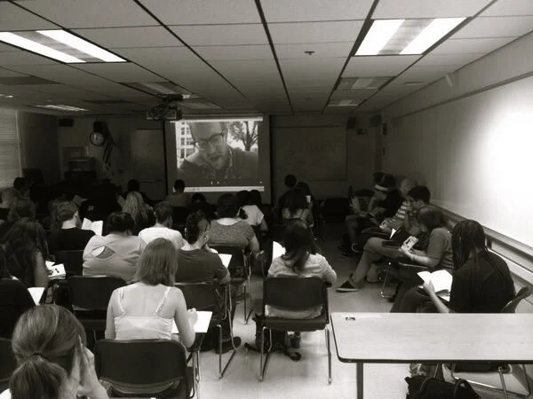 Yesterday, while Skyping with Joshua Marie Wilkinson’s poetry class at the University of Arizona, I was asked to read poems to a classroom of over 50 students, but the computer on their end had no camera and no speaker. I was sitting at a table in the center of PSU’s Urban Plaza, reading poems loudly into my computer without being able to see or hear anything on the other end, without knowing if anything was working, without being able to interact with anyone, without seeing anyone’s expressions or hearing anyone’s laughs. I was just reading poems into the air of the public plaza, and I had to trust that they were going somewhere. Reading poems like that was everything like what writing poems feels like.
At one point, a deaf man approached me and handed me a card that invited me to give him a few bucks. I was in the middle of reading a poem about being on an airplane shouting I love you I love you without anyone being able to hear me when this deaf man interrupted me. He didn’t know I was reading poems to a room of 50 people in Arizona–he didn’t know they were watching us. Neither one of us could hear or see anything in Arizona as everyone in Arizona could hear and see us just fine. I told him I was busy, but he couldn’t hear me. I felt dumb for doing that. He couldn’t hear me, and I couldn’t hear anyone in Arizona. He pointed to the card but all I could do was say I was sorry and make a weird I’m sorry gesture that eveyone in Arizona could see, and I handed his card back to him. Then I continued to read the poem about no one being able to hear me while I could hear no one in Arizona and while the man who couldn’t hear me was walking away. There was a dead mouse a few feet away that whole time too, its skull crushed flat on the bricks. I stepped on its already dead body before any of this. I can still feel its body in my arches.