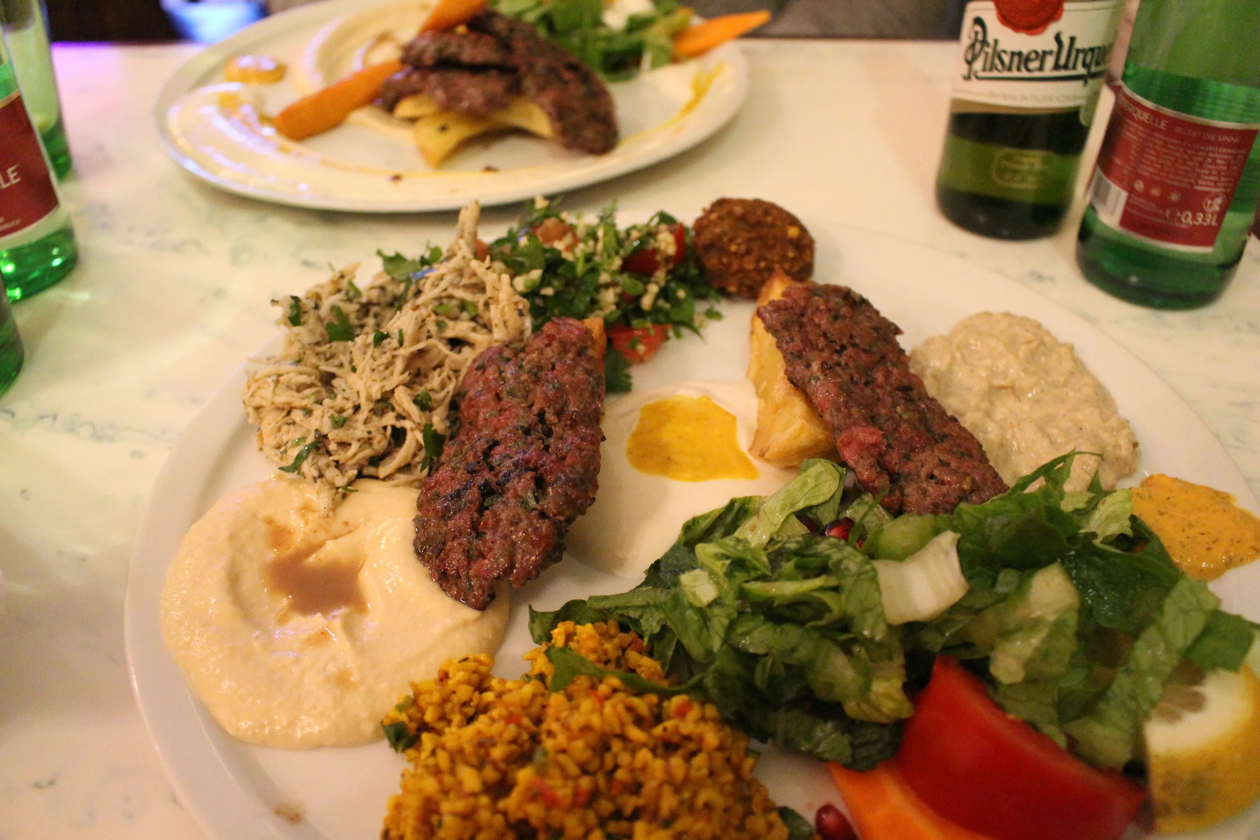 The Mixed Dish from Yarok in Berlin, Germany. Falafel, haloumi, zucchini fritters, Makaly, Huomus, Tabula, couscous, and mutabel 