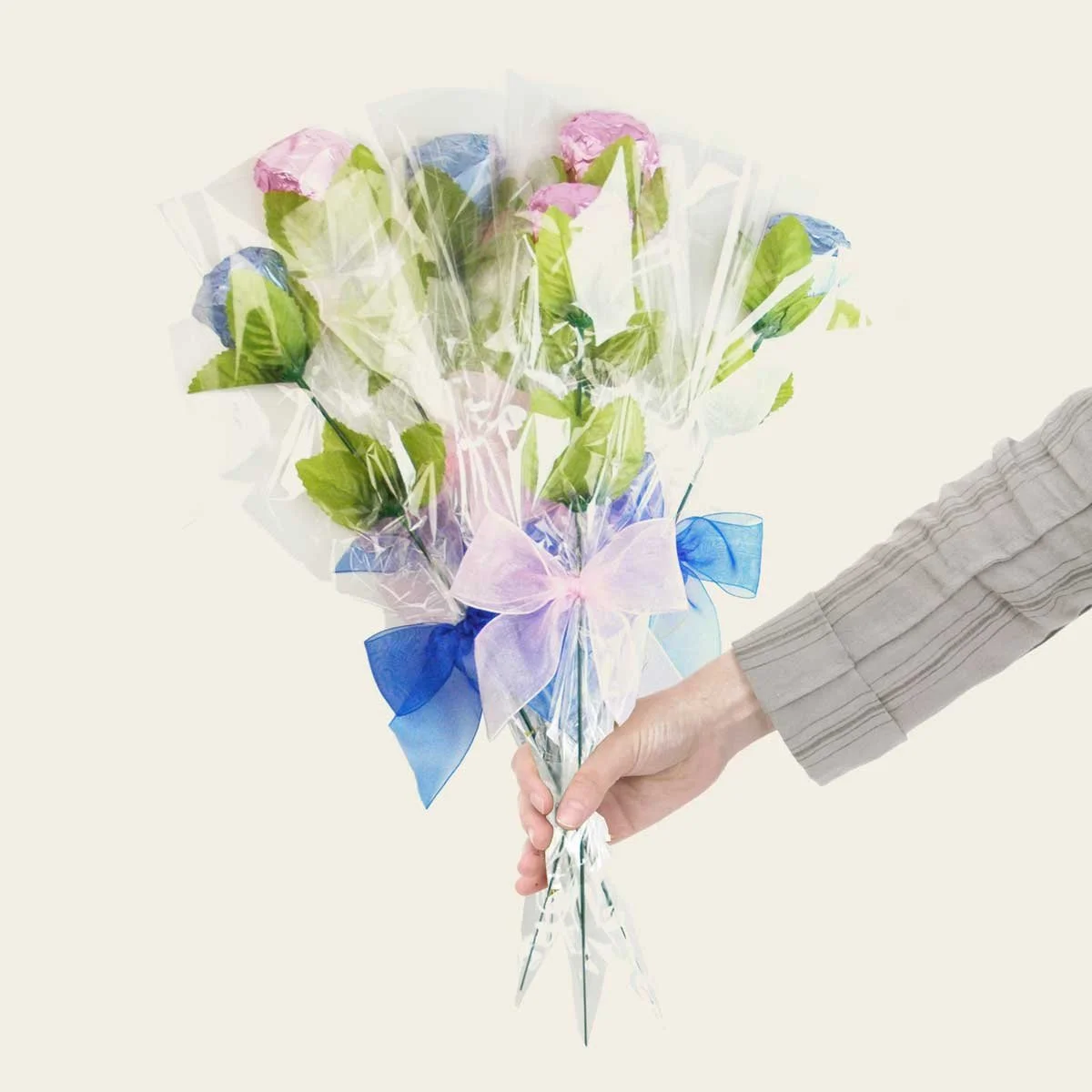 Hand holding a pastel-wrapped bouquet of chocolate gifts