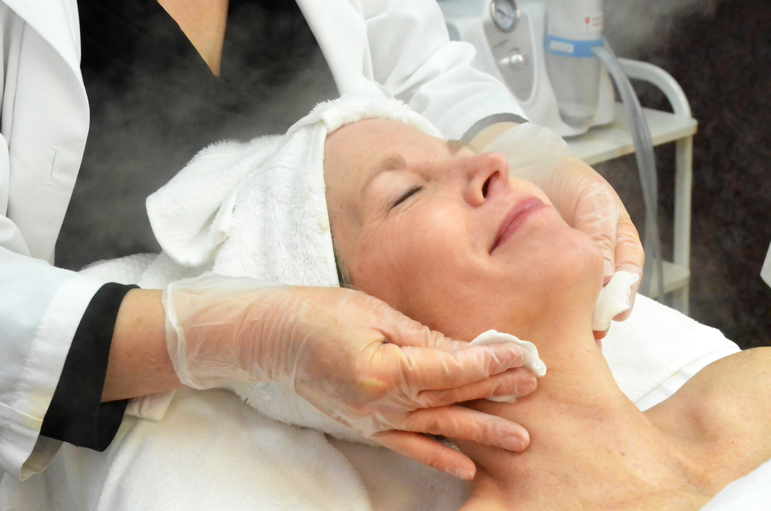 A client looks happy and relaxed while receiving a steam treatment during a rejuvenating facial