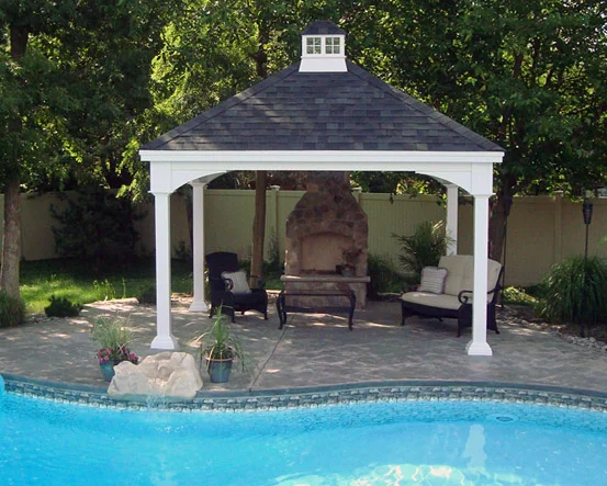 Backyard pool with a gazebo, lounge chairs, potted plants, and an outdoor fireplace.